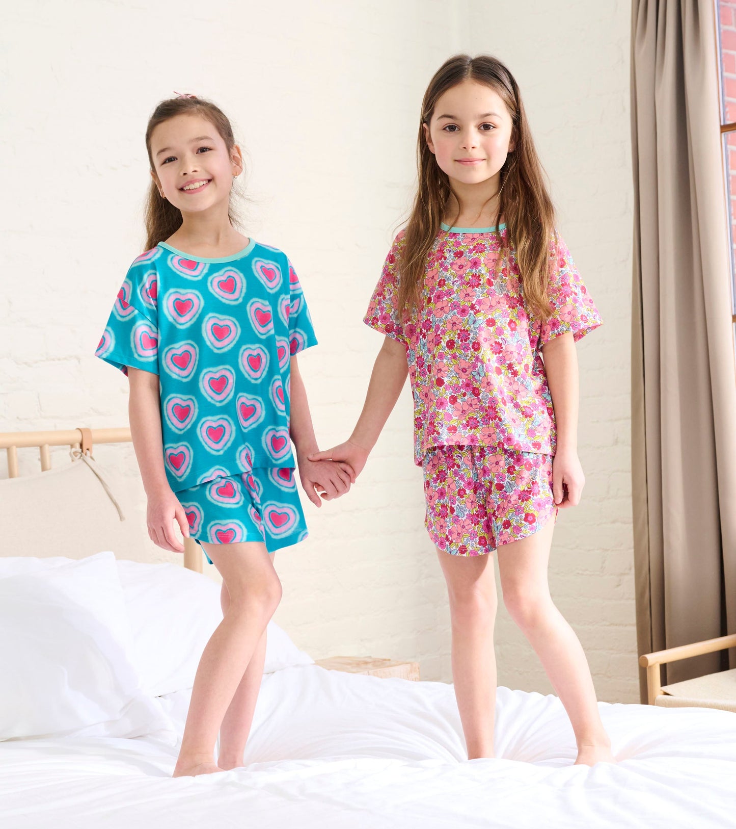 Girls' pajama set featuring a turquoise top with heart patterns and a pink floral design, paired with matching shorts.