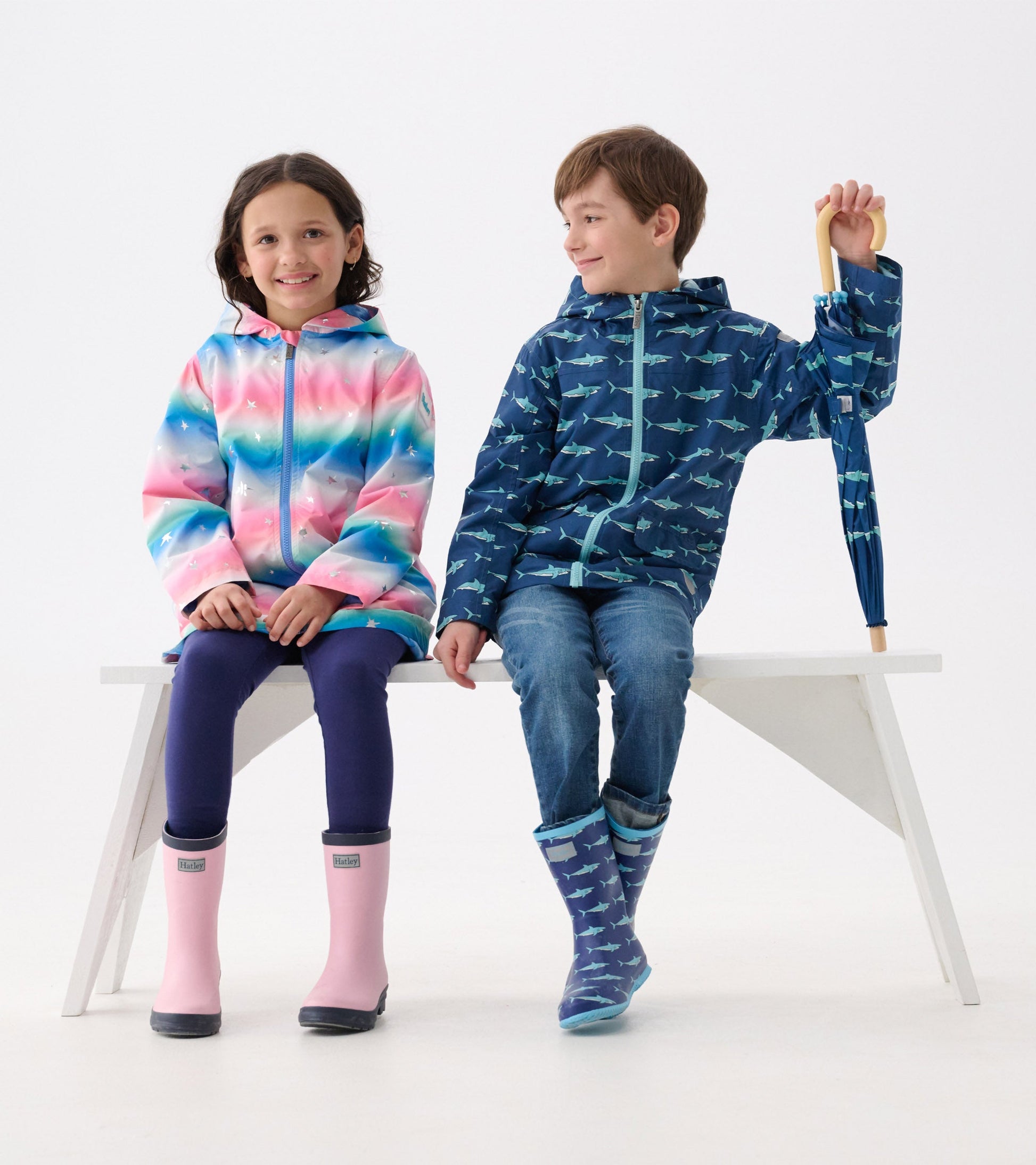 Colorful A-line swing jacket with glitter stars, worn by a girl, paired with a blue shark-patterned jacket on a boy.