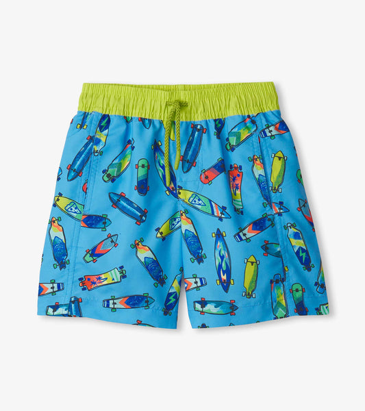 Blue swim trunks featuring a colorful skateboard pattern and a green elastic waistband with drawstring.