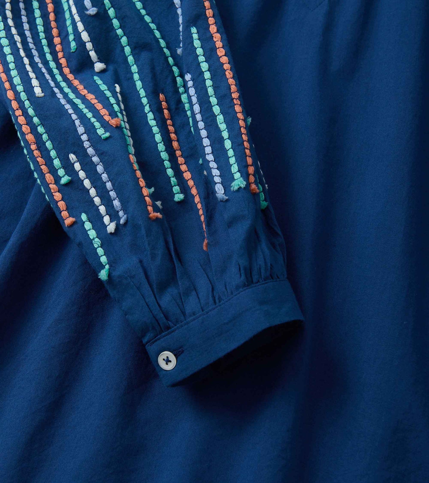 Navy blue tunic featuring colorful embroidered details on the sleeve and a buttoned cuff.
