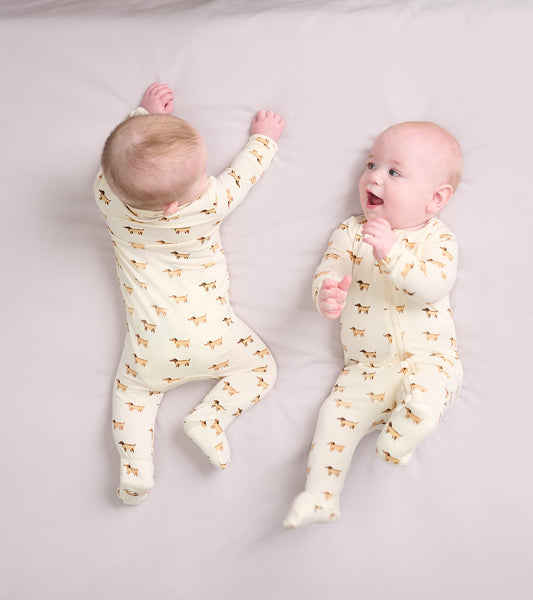 Cream footed sleeper with mini hot dog print, worn by two babies, one smiling and the other reaching out.