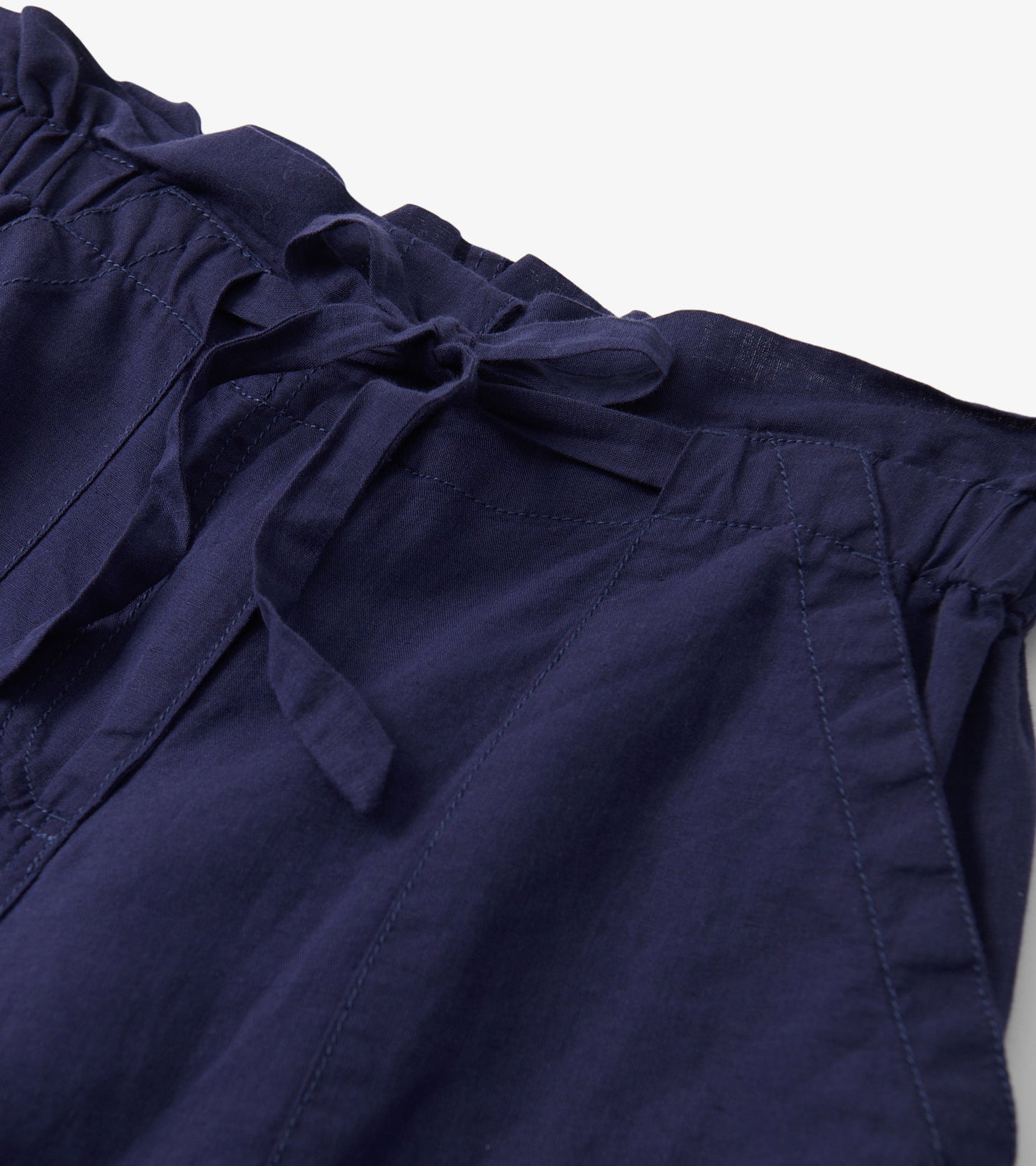 Close-up of navy blue pants with a tie waist and visible stitched seam details