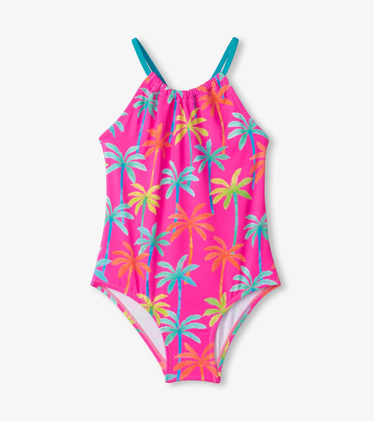 Bright pink swimsuit with colorful palm tree print and gathered front, featuring adjustable teal straps.