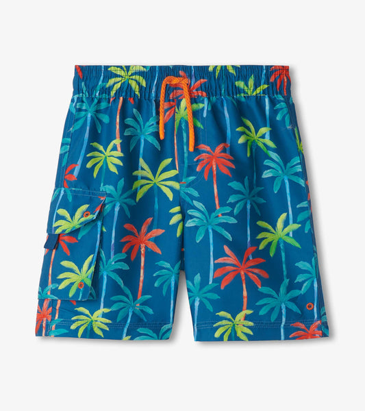 Blue board shorts featuring a vibrant palm tree print in green, yellow, and red, with an elastic waistband and side pocket.