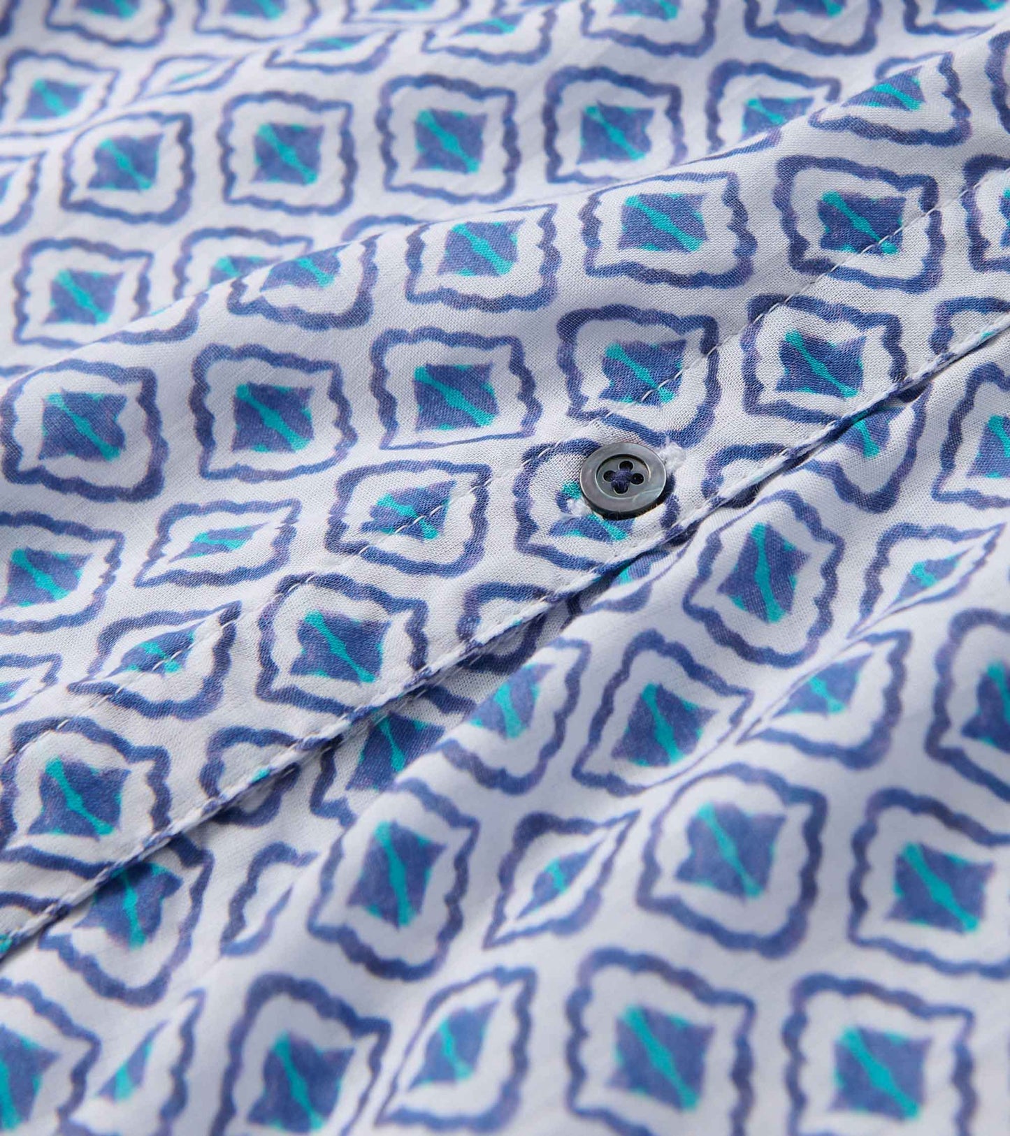 Light fabric blouse featuring a painted petal pattern in blue and green hues with a button detail.