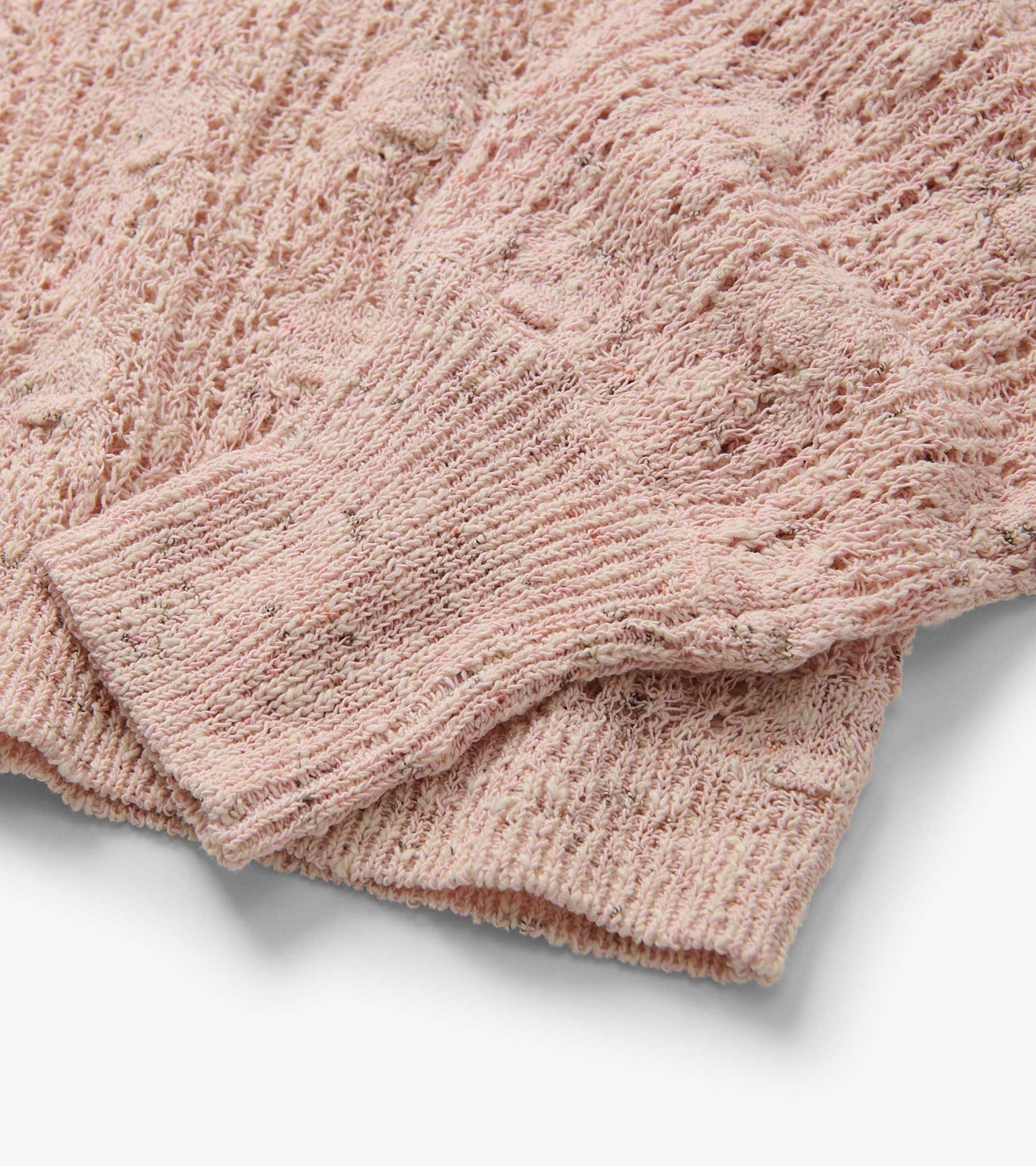 Light pink pointelle sweater with textured knit pattern and ribbed cuffs, showcasing a soft, feminine design.