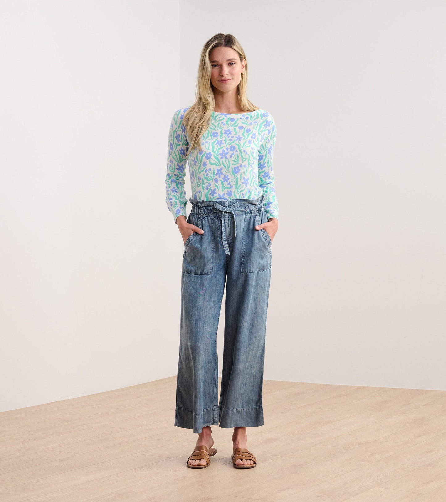 Light blue 3/4 sleeve knit top with painted floral pattern, paired with loose denim pants, model standing on wooden floor.