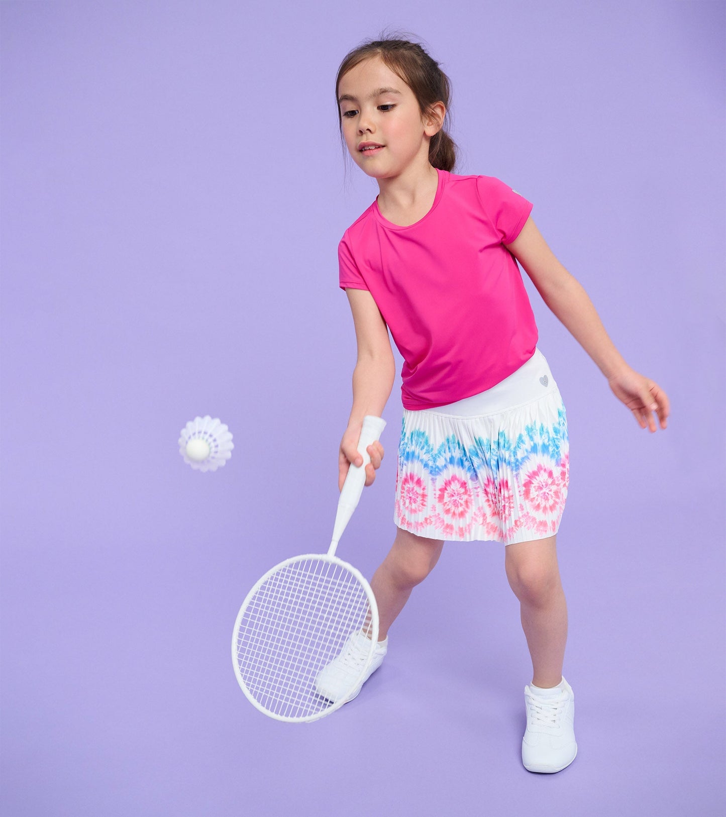 Bright pink short-sleeve T-shirt with mesh trim, worn by a girl playing badminton against a purple background.