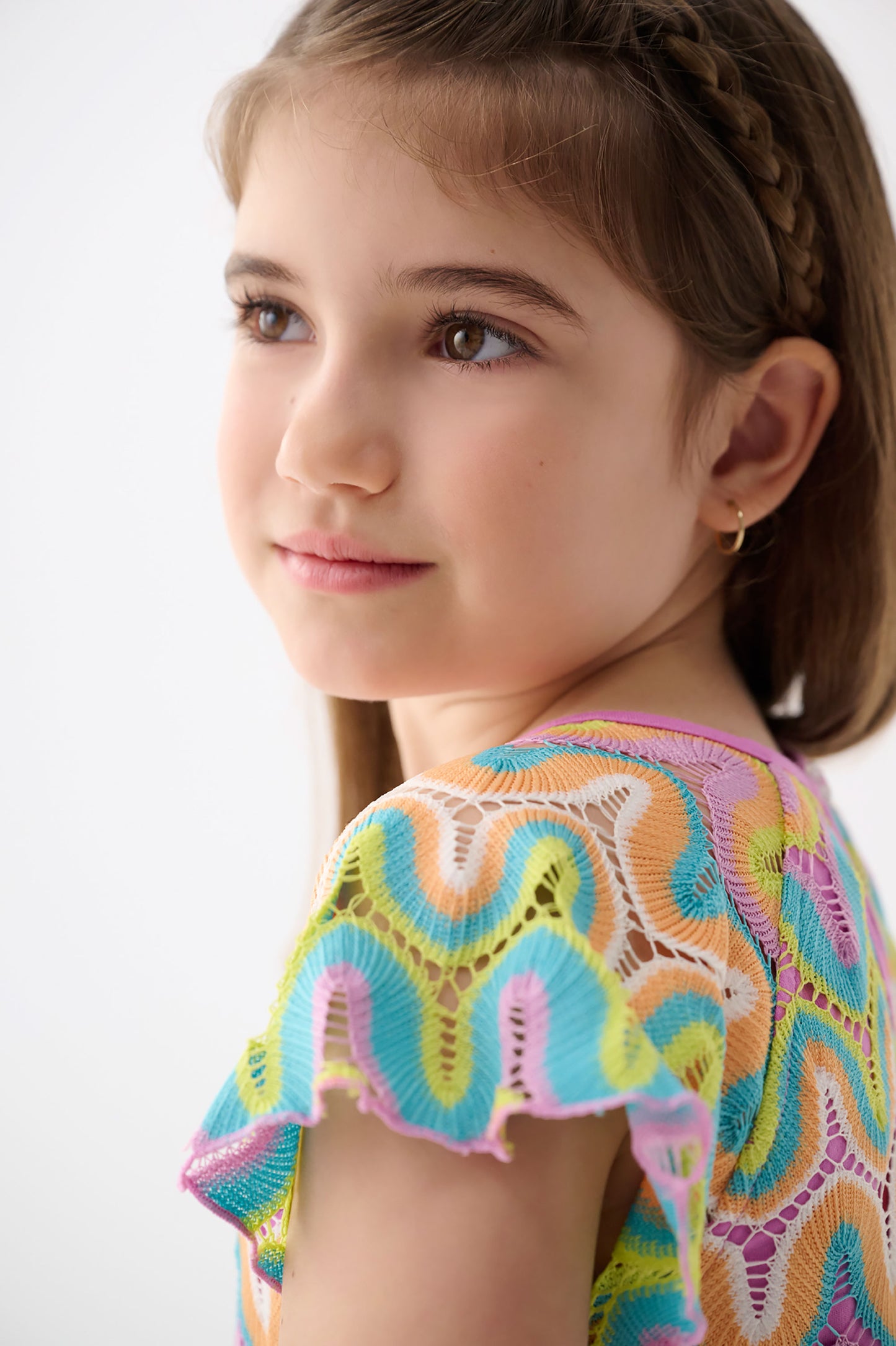 Colorful crochet dress featuring rainbow wave patterns and scalloped sleeves, perfect for warm weather wear.