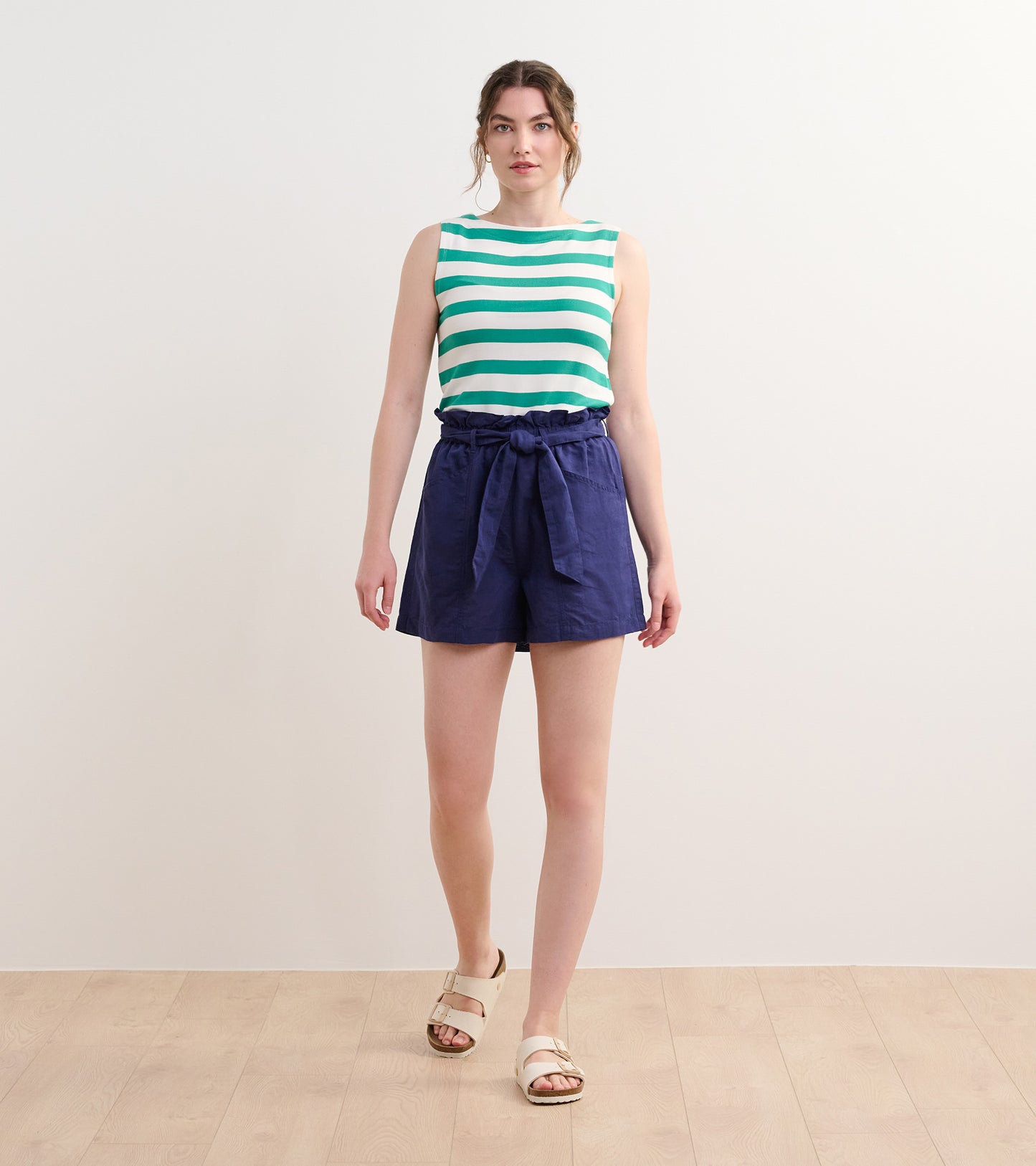 Sea green and white striped tank top paired with navy shorts, featuring a tied waist and casual sandals.