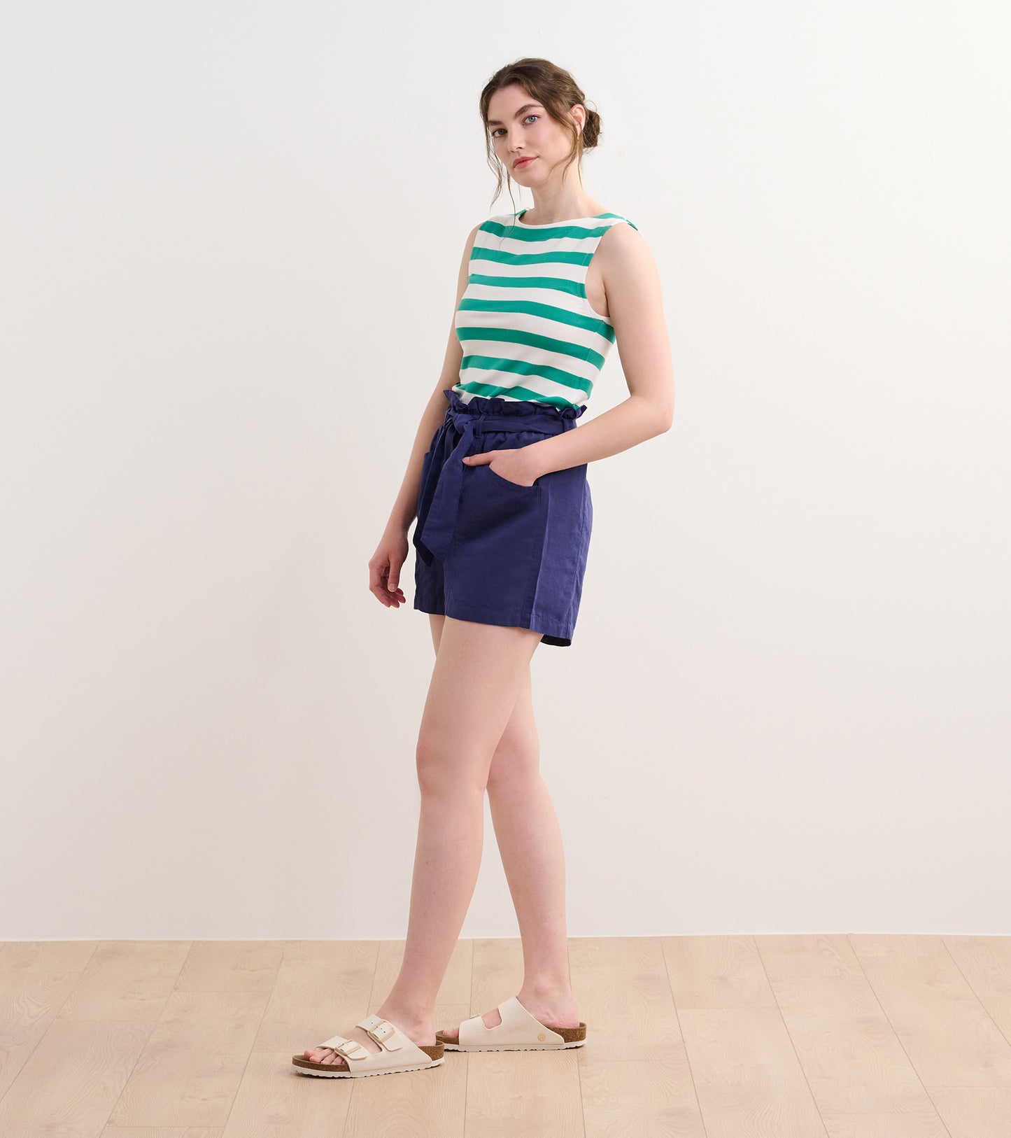 Sea green striped tank top with a round neckline, paired with navy shorts, styled for casual wear.