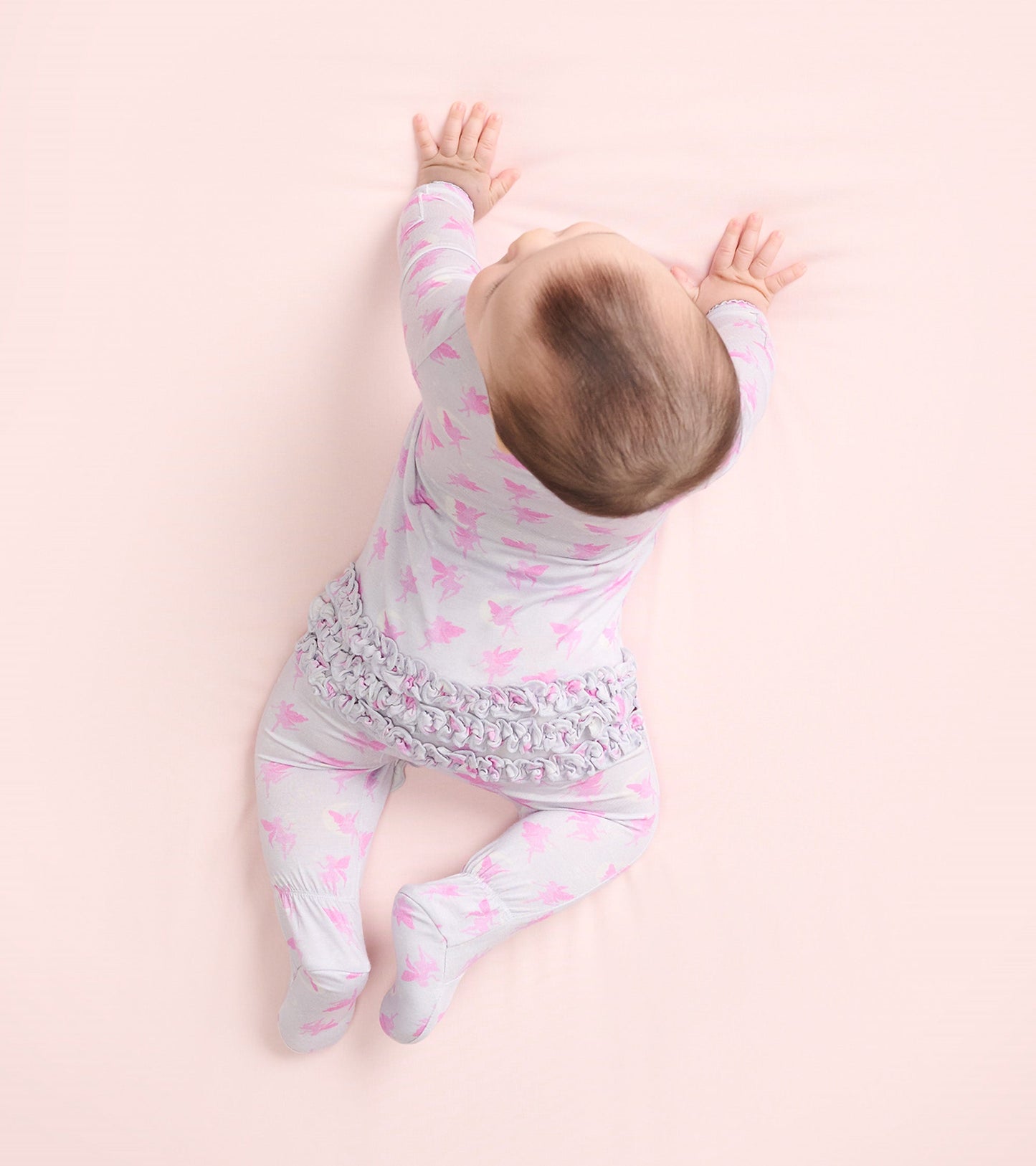 Light gray footed sleeper with pink fairy print and ruffled waistband, designed for baby girls, shown from above.