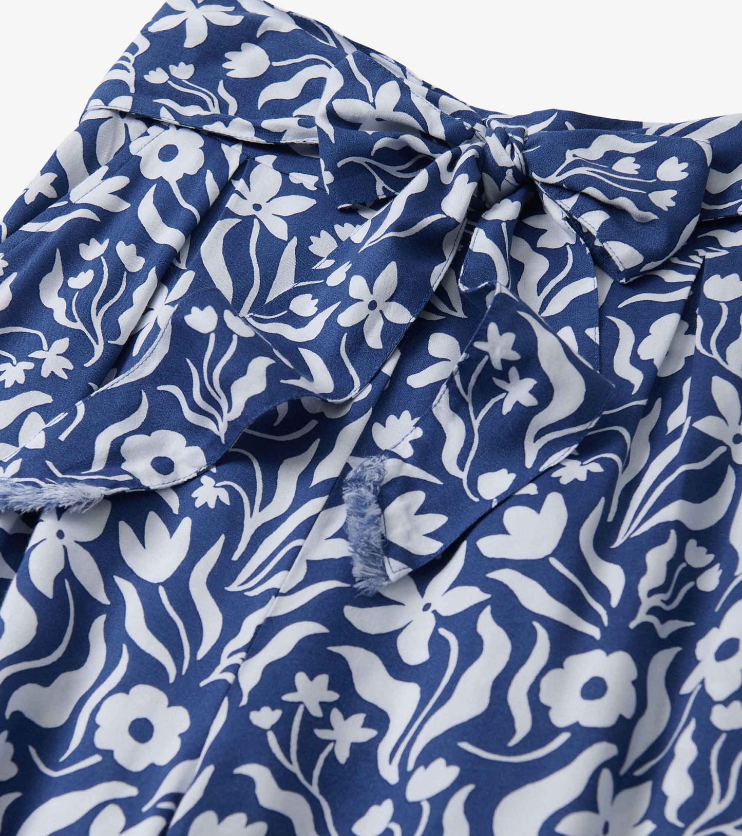 Navy wide leg pants featuring a white wavy floral pattern and a belted waist detail.