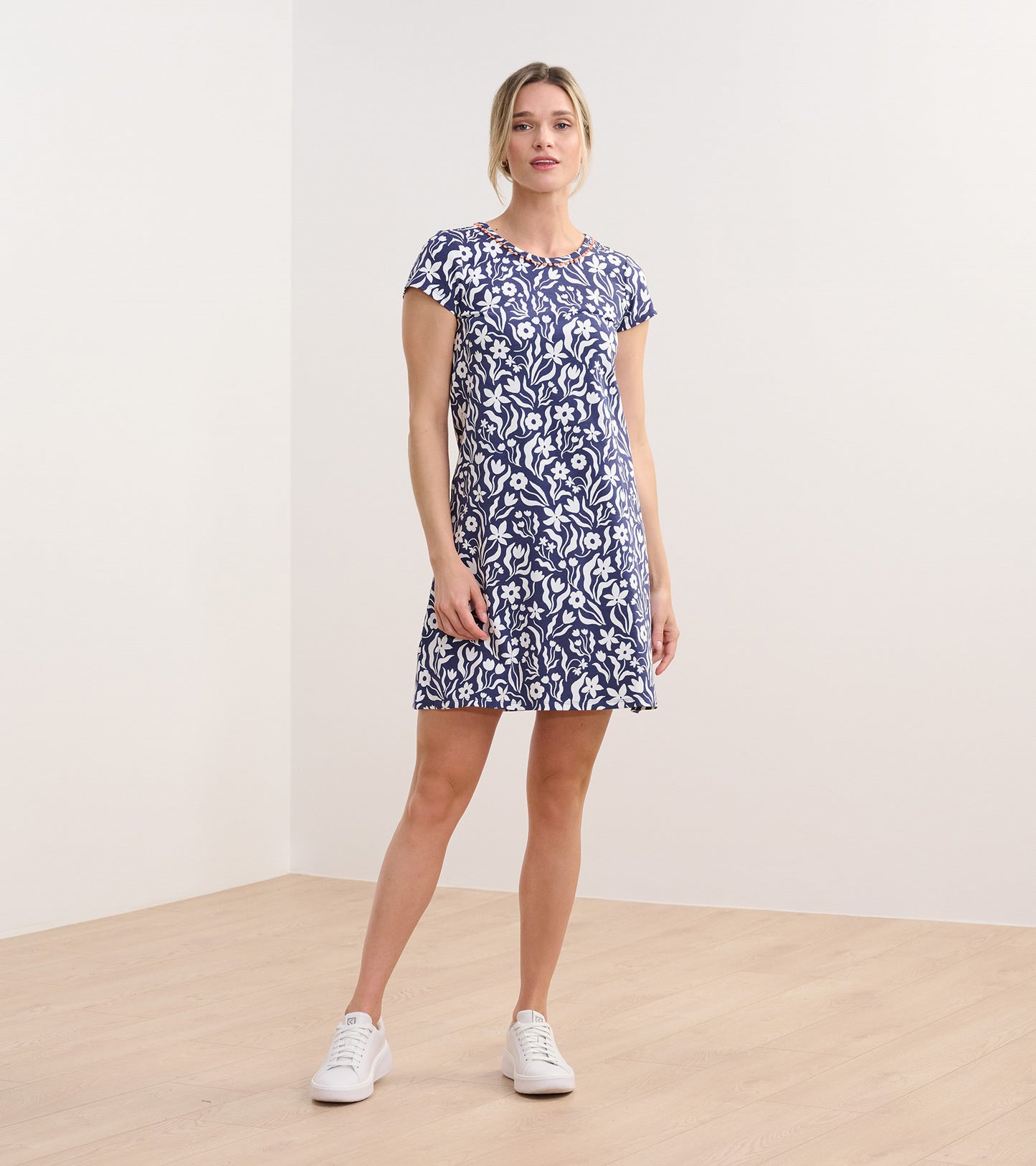 Navy A-line dress with wavy white floral pattern, short sleeves, and a round neckline, styled with white sneakers.
