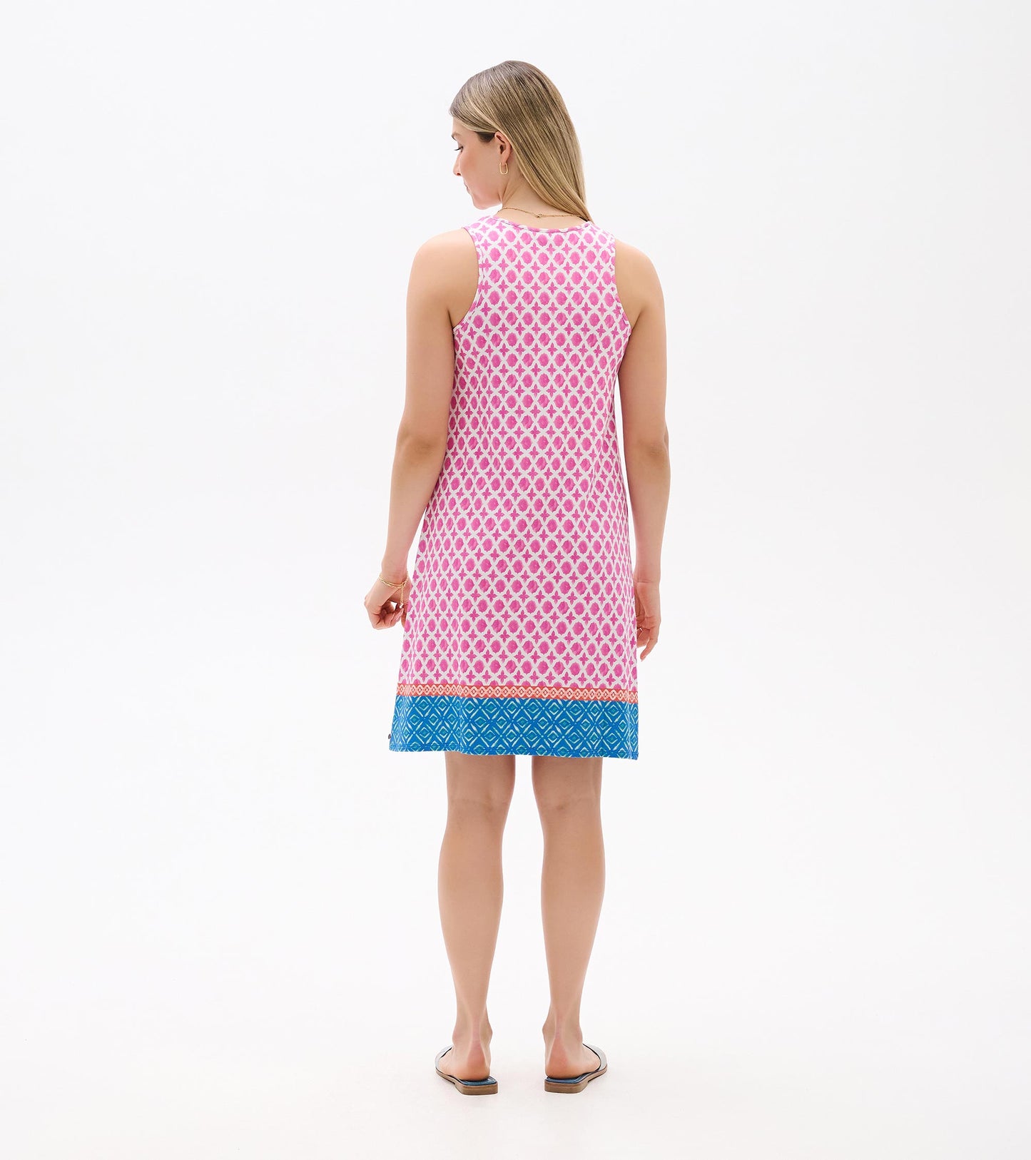 Back view of a sleeveless pink patterned dress with blue geometric hem and white trim.