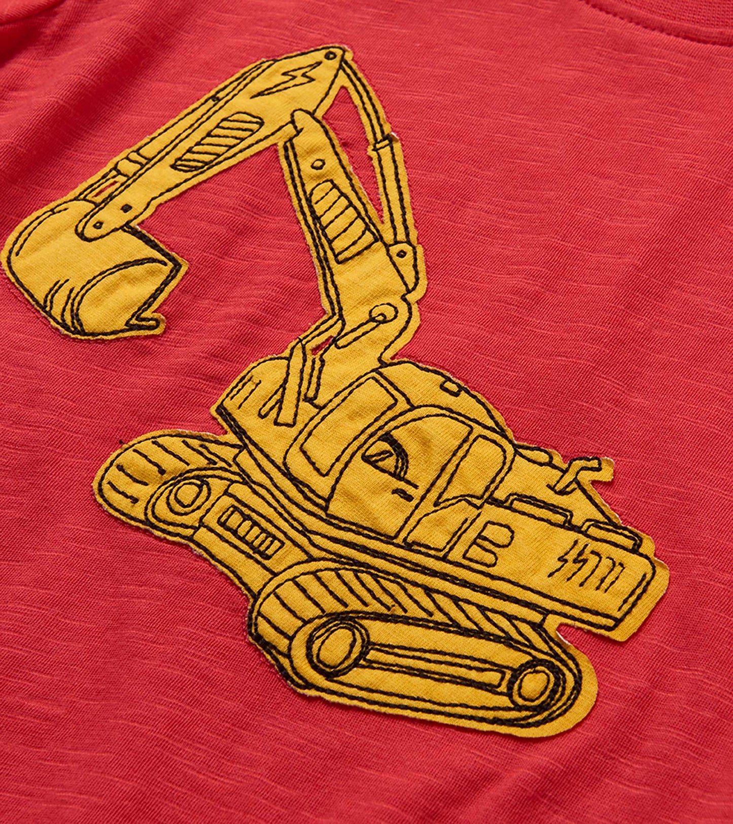 Red toddler T-shirt with yellow excavator graphic on textured fabric, close-up view