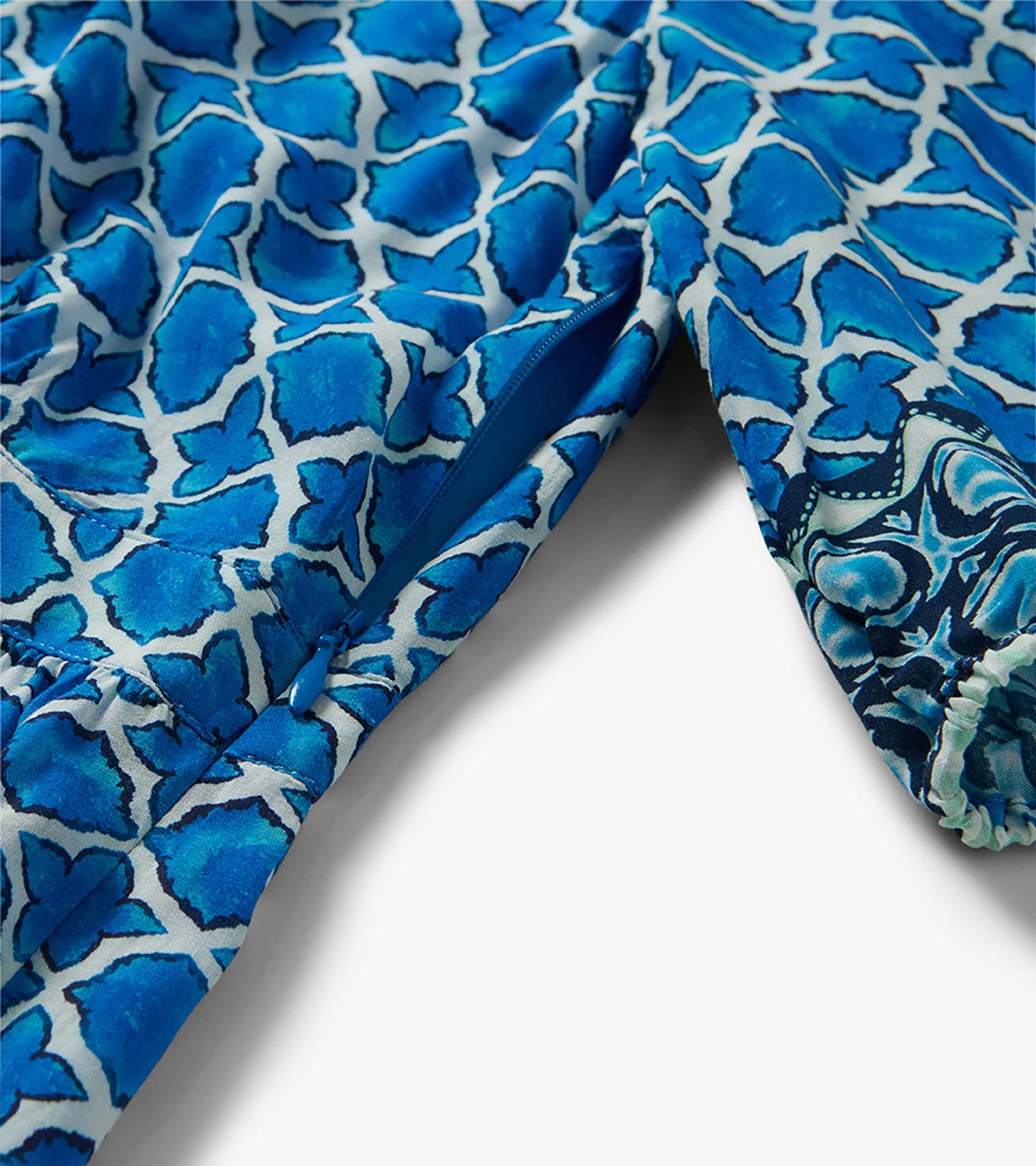Blue floral patterned dress fabric with zipper detail and gathered sleeve cuff close-up
