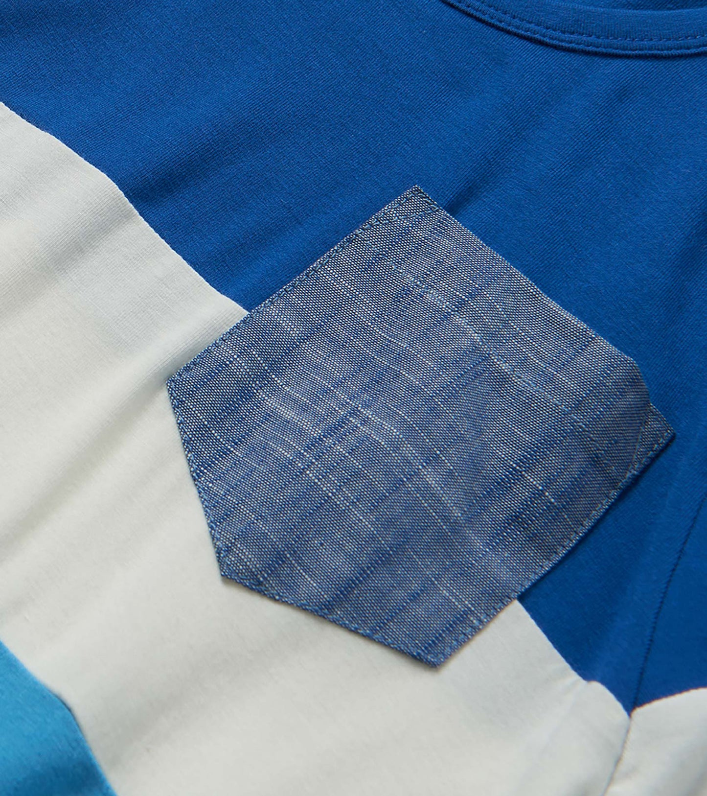 Close-up of a blue, white, and light blue color-block bamboo T-shirt fabric with stitched patch detail