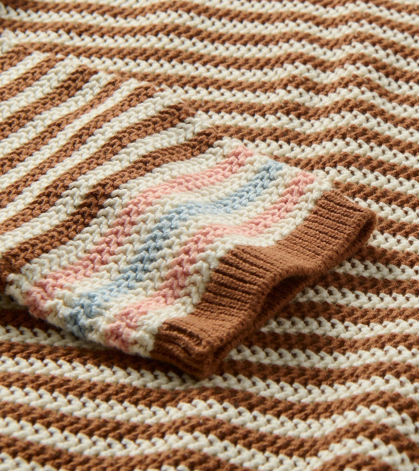 Close-up of brown and cream striped pointelle knit with pink and blue striped cuff detail