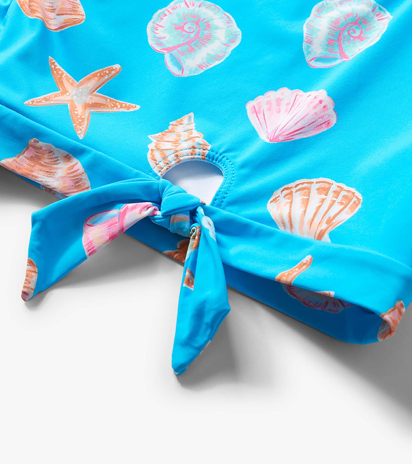 Blue girls’ swimsuit bottom with seashell and starfish print, tie-front detail, close-up view