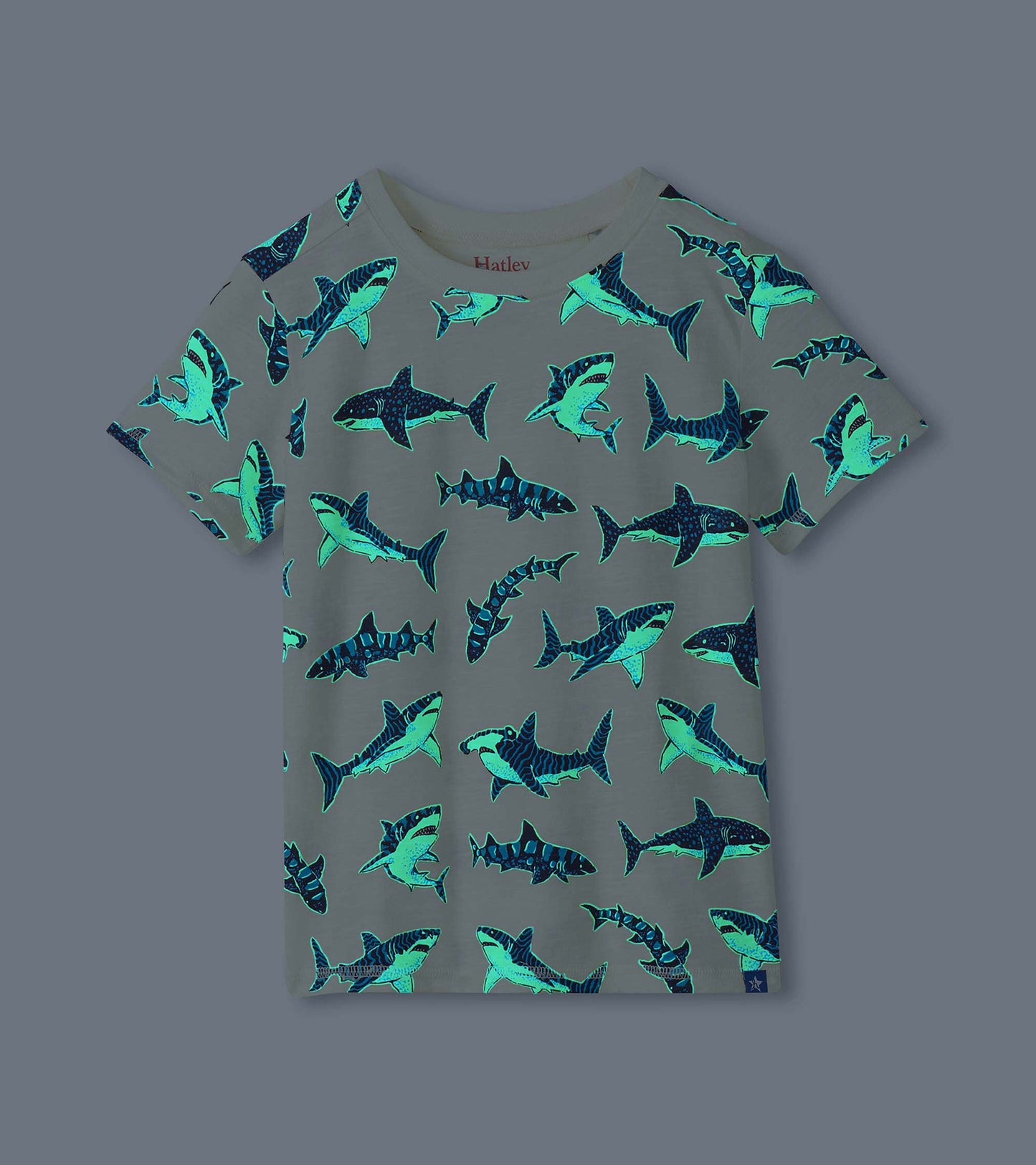 Cream boys shark print tee shown glowing in the dark with bright blue shark outlines