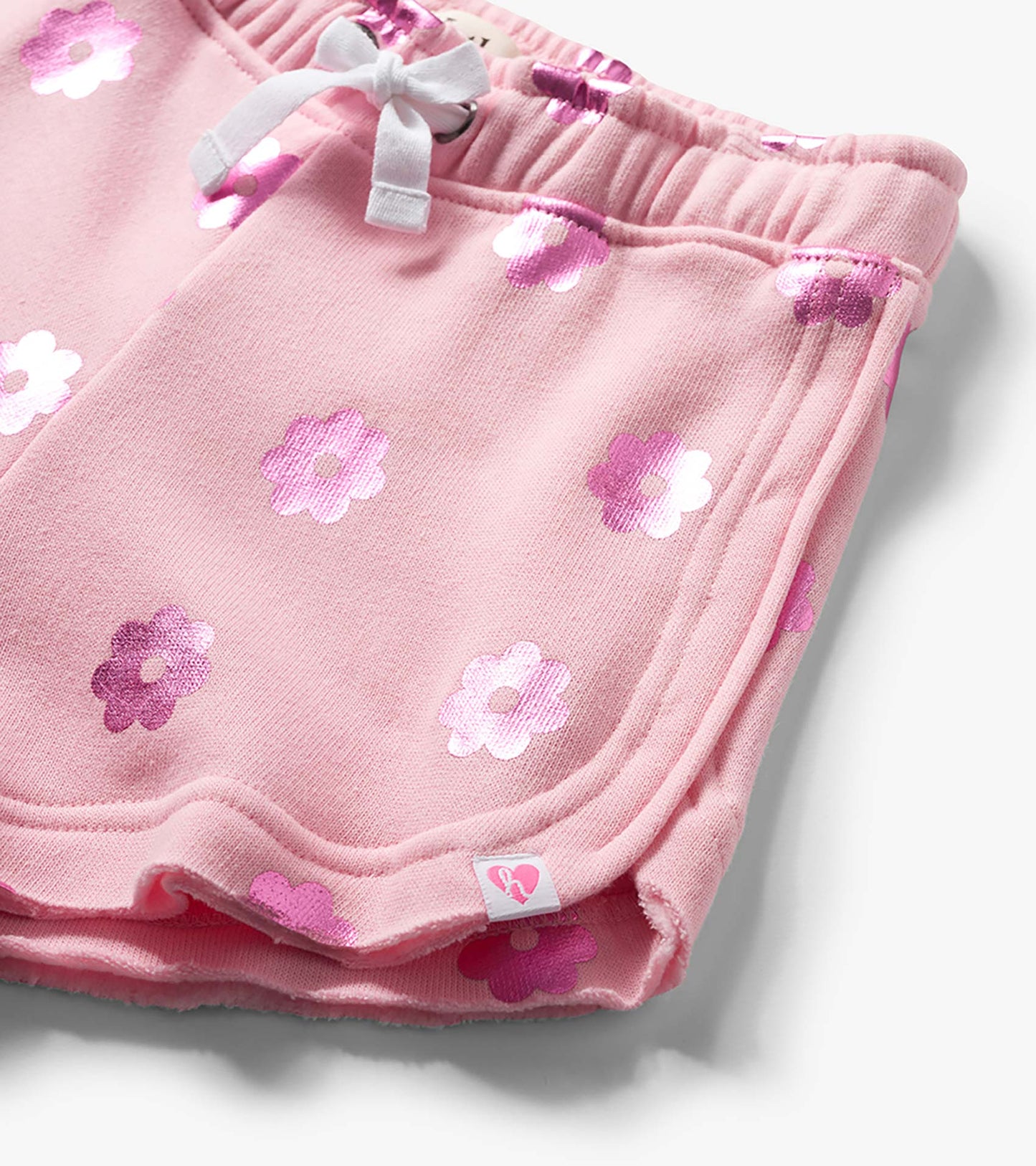 Pink pull-on shorts with white drawstring and pink floral print, close-up front view