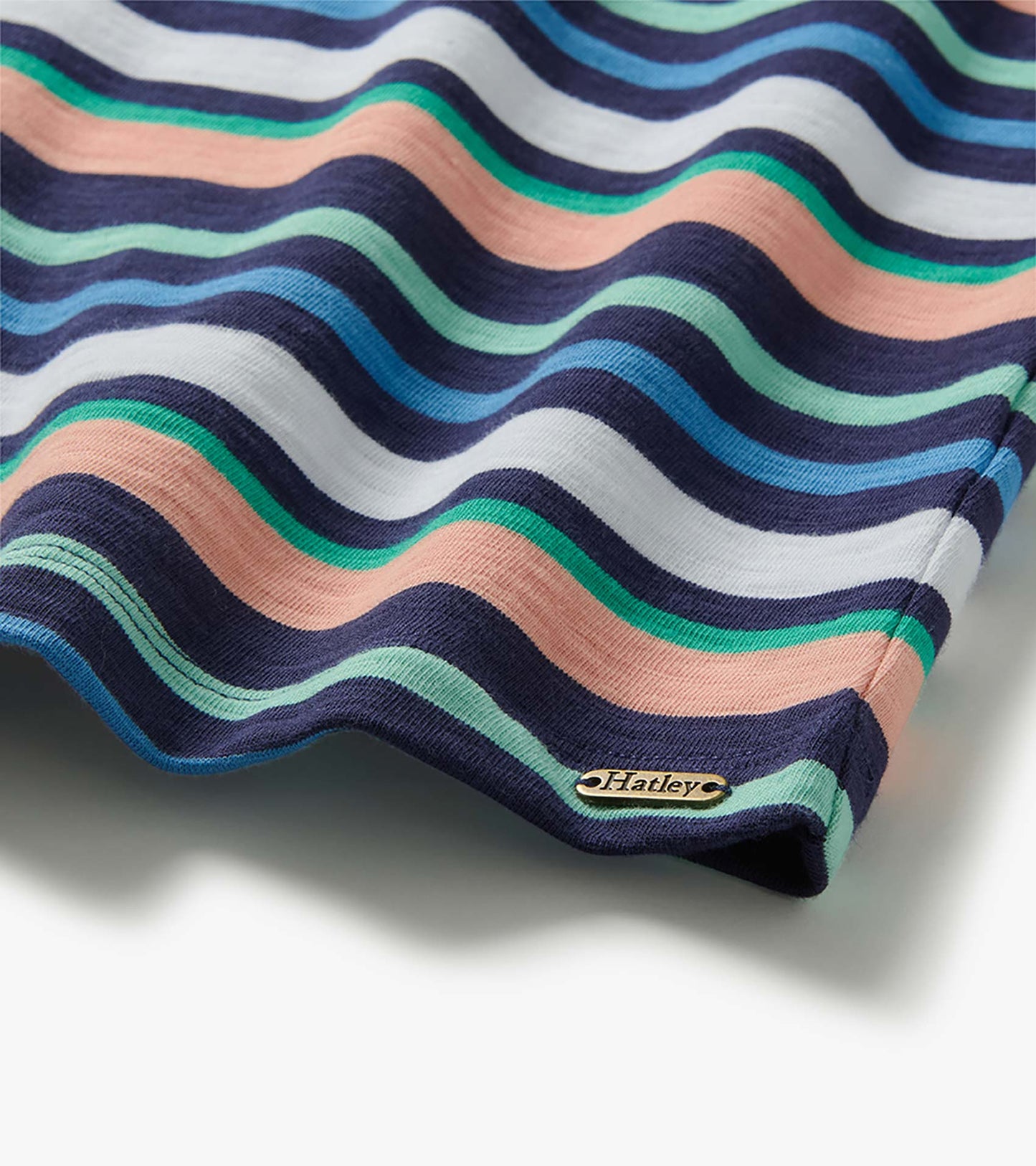 Close-up of Seaside Stripes dress hem with navy, white, blue, mint and peach wavy stripes and Hatley tag