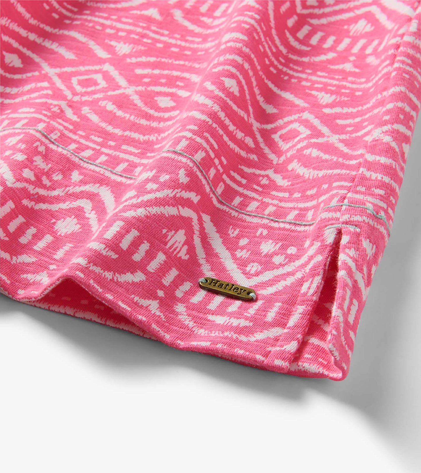 Close-up of pink and white sketched line pattern dress hem with visible Hatley metal logo tag