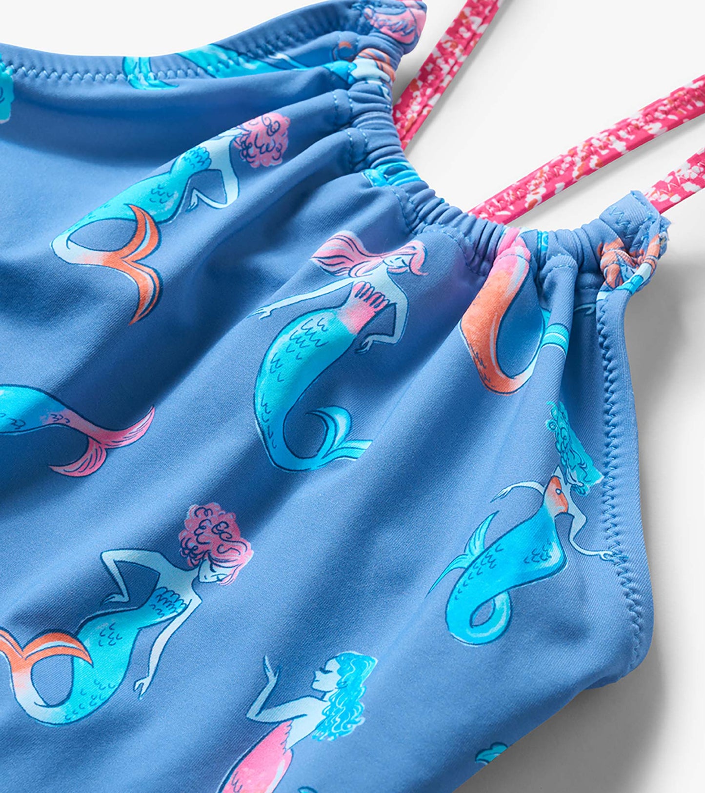Blue girls one-piece swimsuit with mermaid print and pink patterned shoulder straps, close-up view