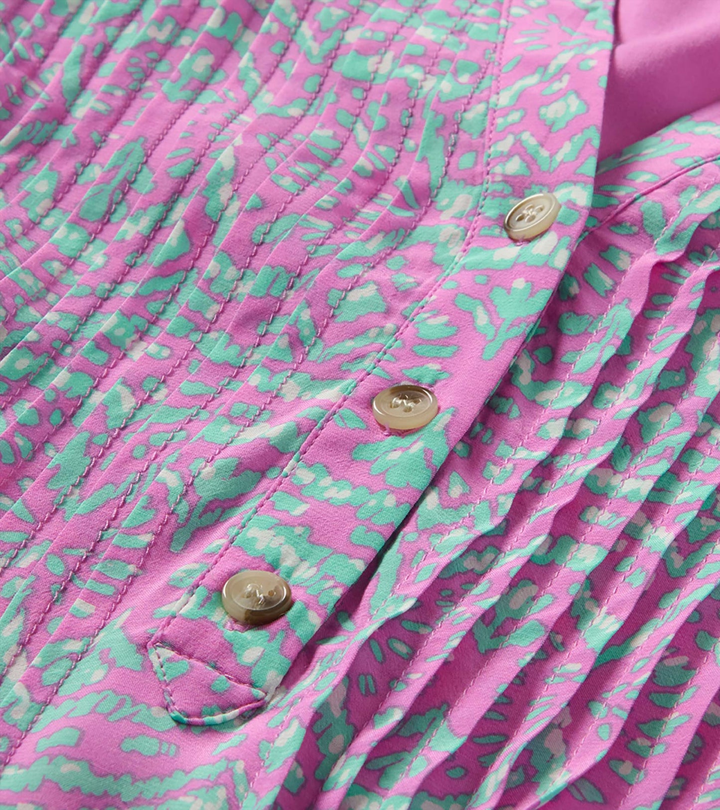 Close-up of pink and mint ikat print dress with pintuck pleats, front buttons, and self-tie belt