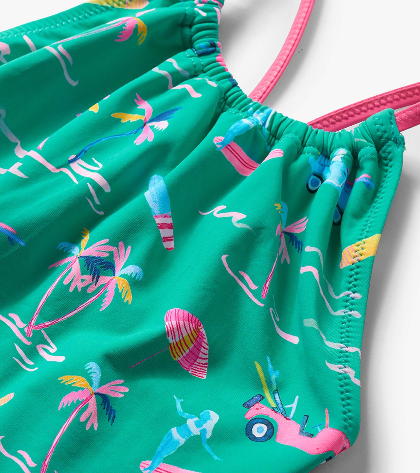Green girls one-piece swimsuit with colorful tropical print and pink straps, close-up view
