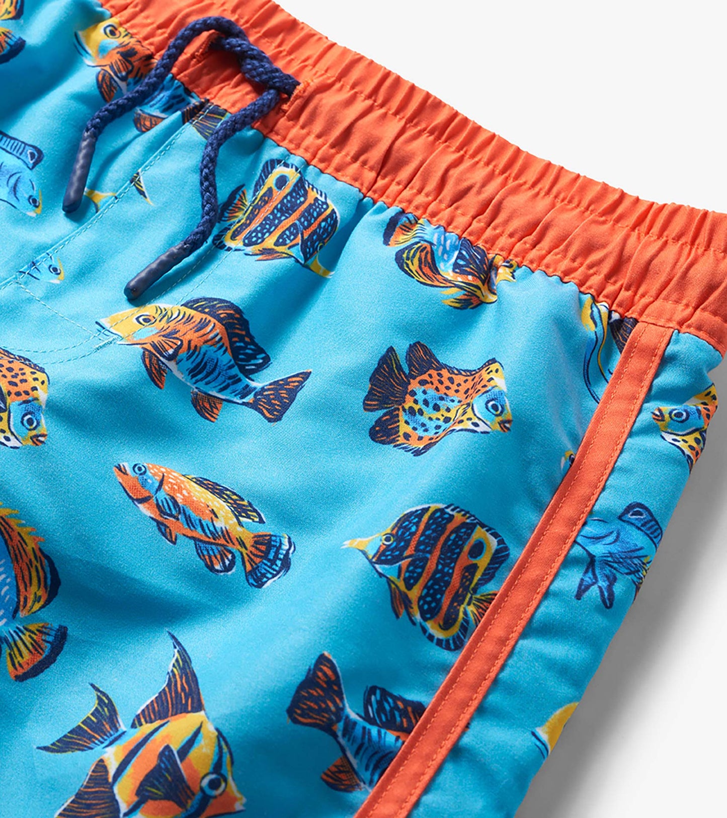 Blue boys swim trunks with orange waistband, fish print, and navy drawstring close-up