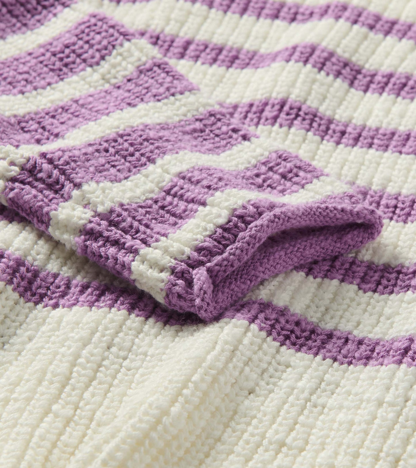 Close-up of ivory and lavender striped knit sweater showing textured stitches and rolled edge