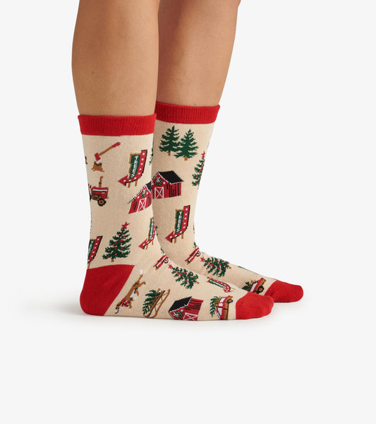 Beige crew socks featuring a Christmas tree farm pattern with red accents and illustrations of barns, trees, and tractors.