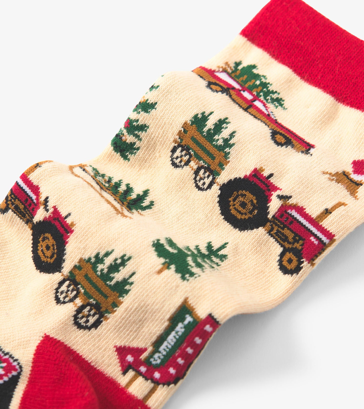 Cream socks featuring a festive pattern of red tractors, Christmas trees, and holiday signs, with a red cuff.