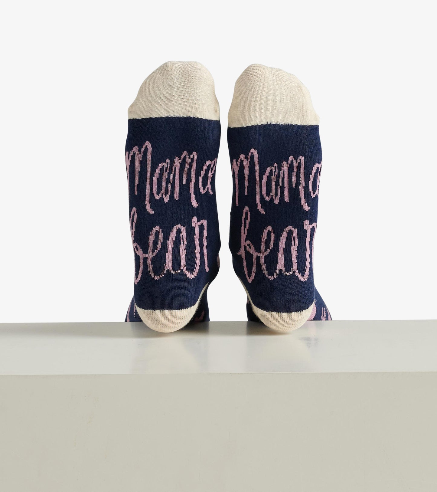 Navy crew socks with pink "Mama bear" text and cream-colored cuffs, displayed from the back.