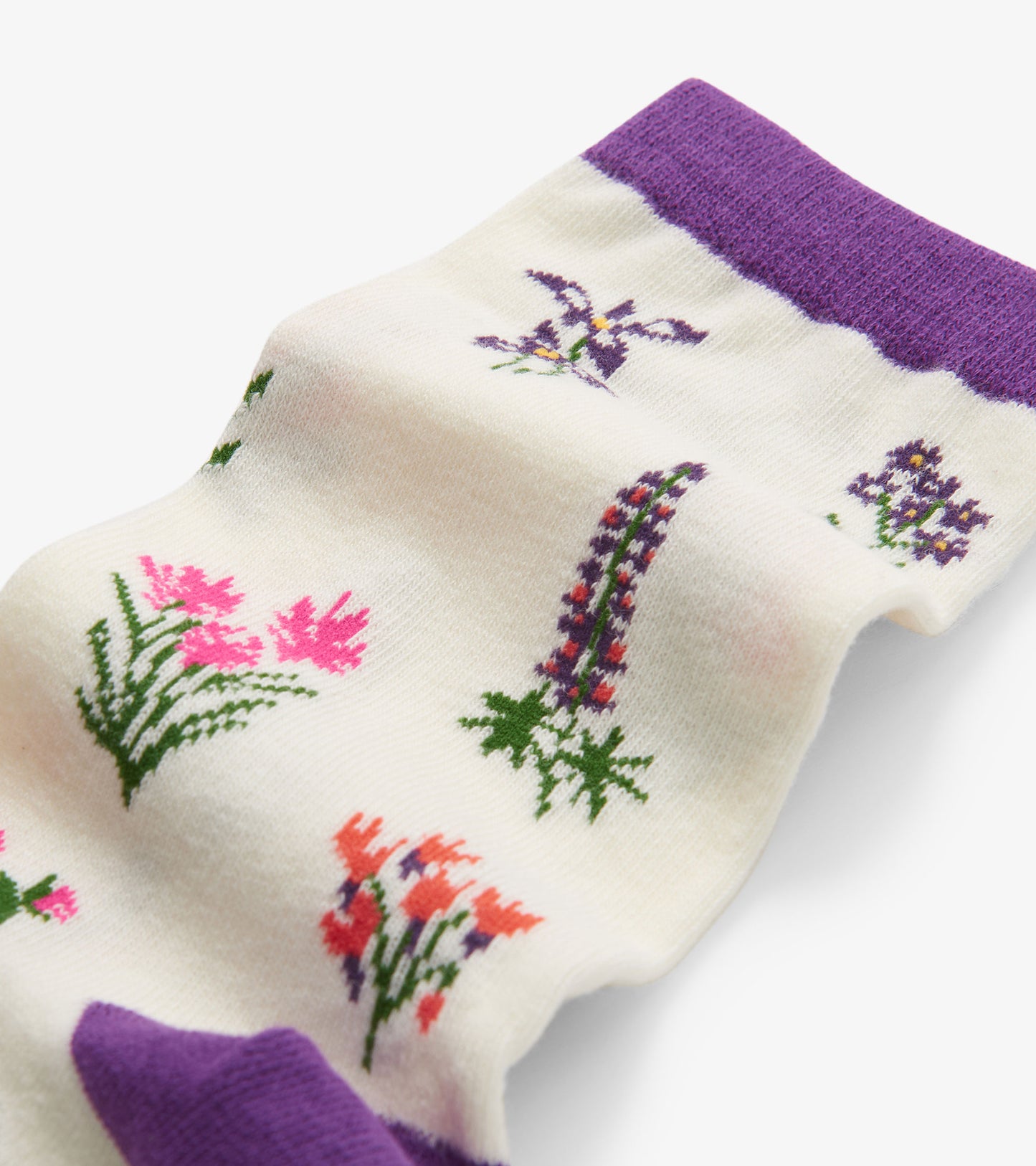 Cream crew socks featuring colorful wildflower patterns and a purple ribbed cuff. One size fits most.