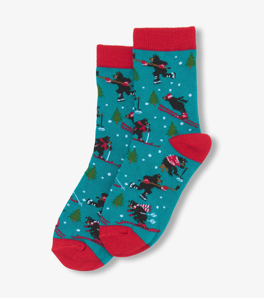 Teal crew socks featuring playful skiing bears, red cuffs, and a winter forest pattern. Ideal for kids' winter wear.