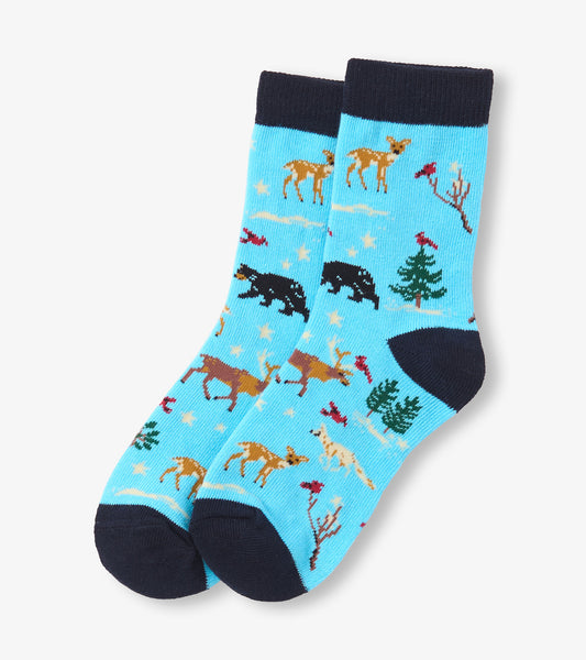 Light blue crew socks featuring a winter wildlife pattern with deer, bears, and trees, accented by a dark navy cuff.