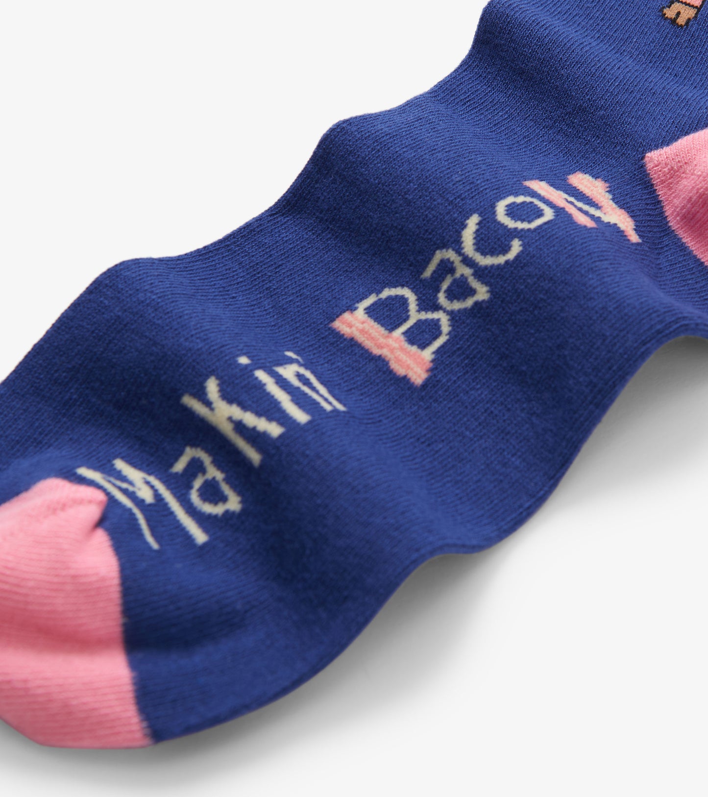 Blue crew socks featuring "Makin' Bacon" text in white and pink accents. One size fits all.