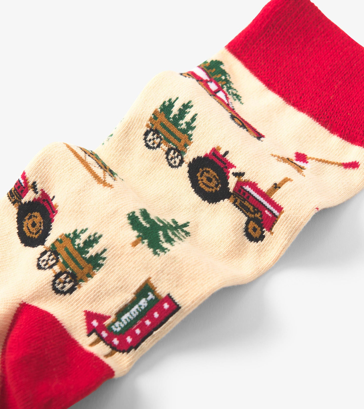 Beige crew socks featuring red accents and festive patterns of tractors, trees, and Christmas farm scenes.