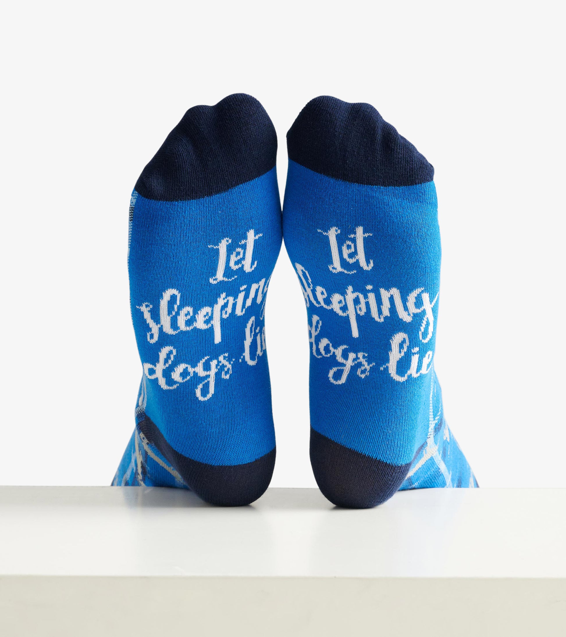 Blue crew socks featuring white text that reads "Let Sleeping Dogs Lie," with a dark blue toe and heel.
