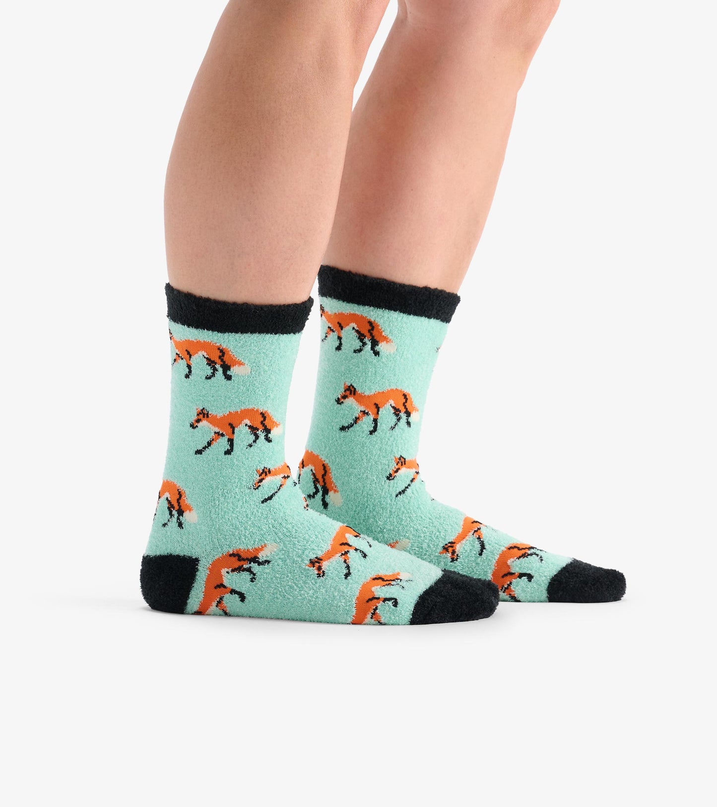 Fuzzy mint green socks featuring playful orange fox patterns and black cuffs, suitable for casual wear.