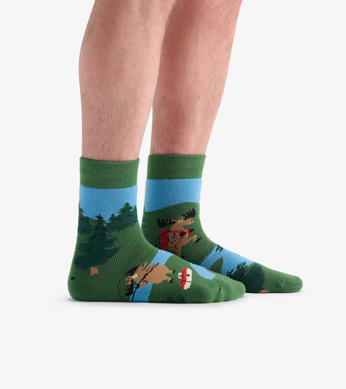 Green cozy socks featuring a moose and forest scene, with a blue band at the top. One size fits most.