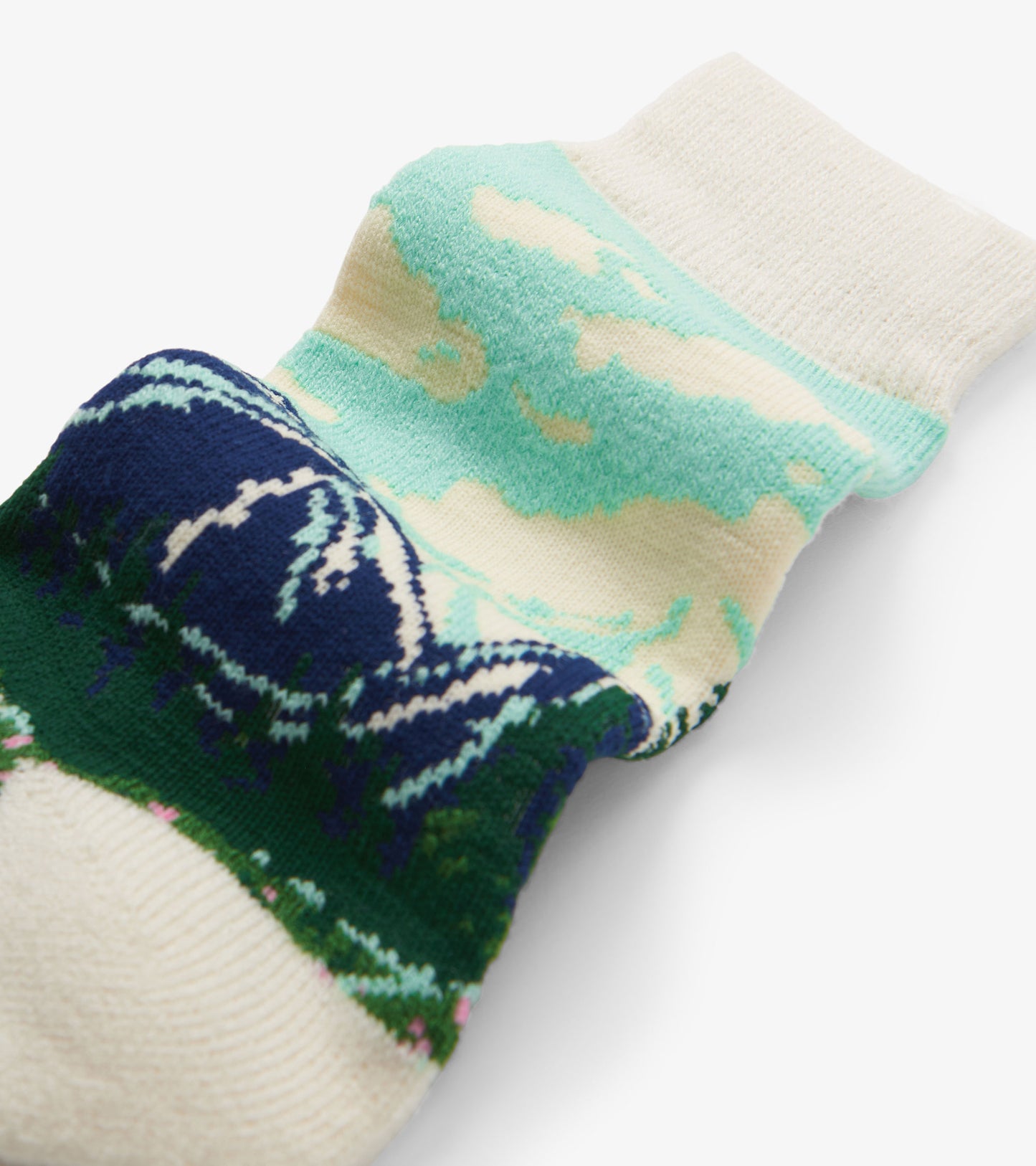 Cozy socks featuring a mountain and cloud pattern in shades of green, blue, and cream. One size fits all.