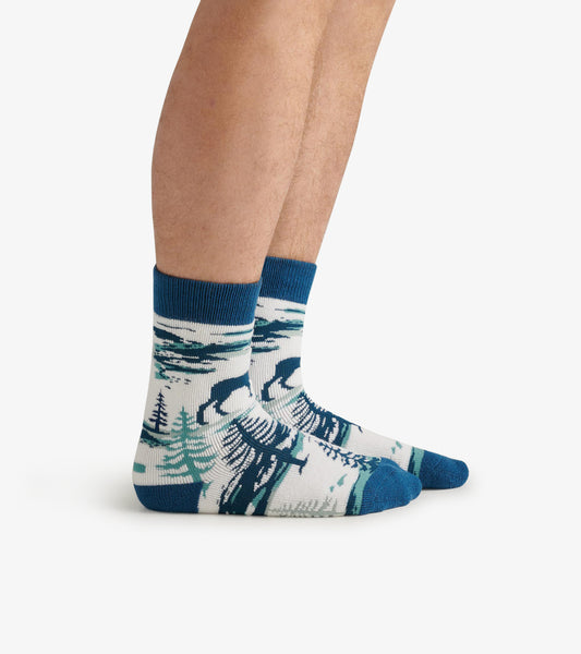Cozy socks featuring a moose and forest design in blue, white, and green, with a ribbed cuff and crew length.