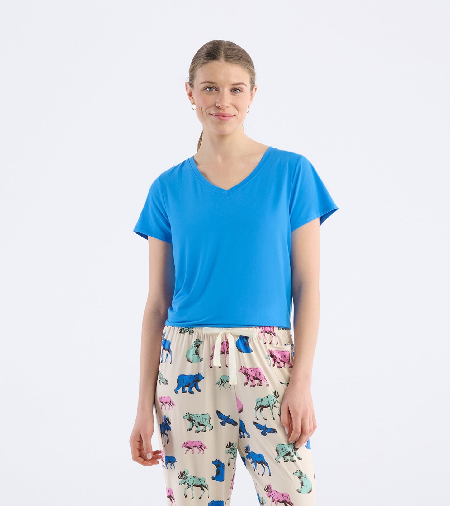 Blue V-neck t-shirt with short sleeves, worn by a model, paired with patterned pants.