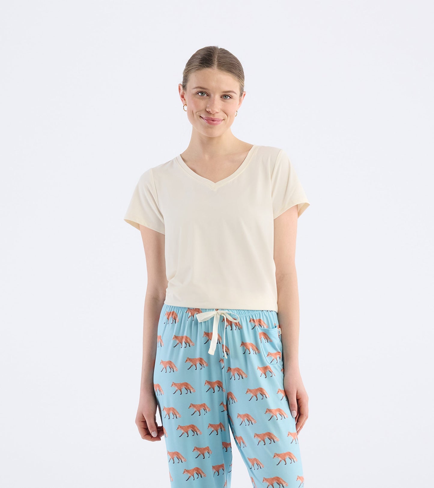 Cream V-neck t-shirt with short sleeves, paired with blue pants featuring a fox print.