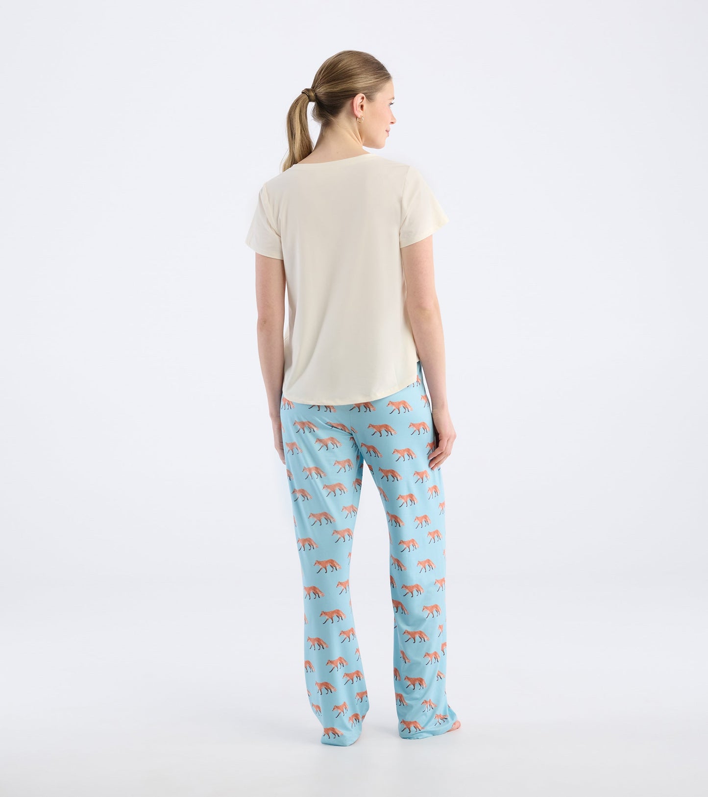 Cream V-neck t-shirt with short sleeves, viewed from the back, paired with patterned blue pants.