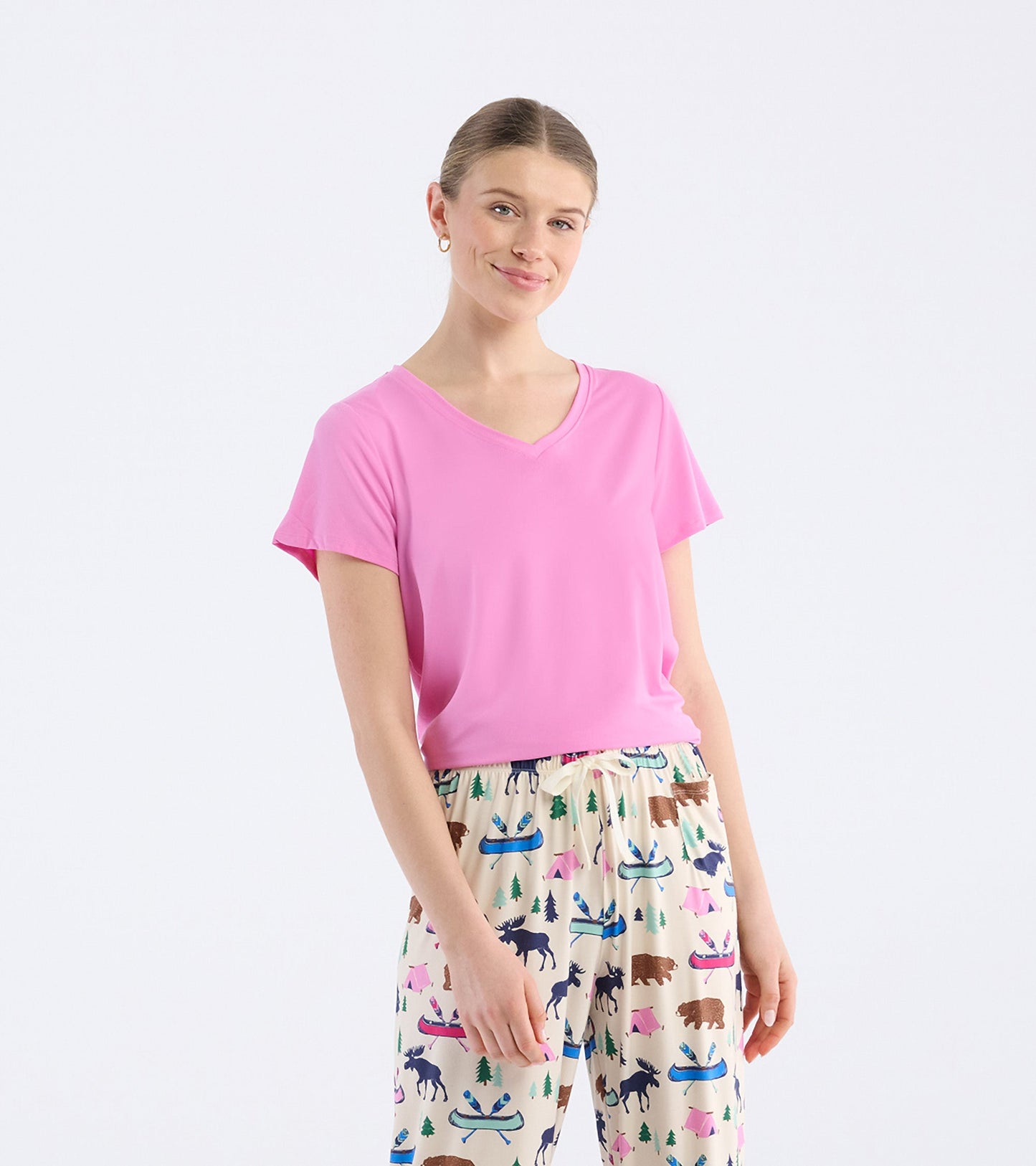 Pink V-neck t-shirt with short sleeves, worn with patterned pajama pants featuring animals and outdoor themes.